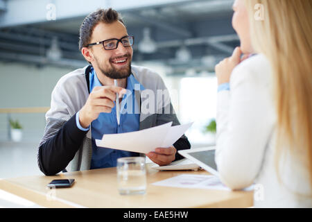 Imprenditore sorridente con documenti parlando al collega di sesso femminile Foto Stock