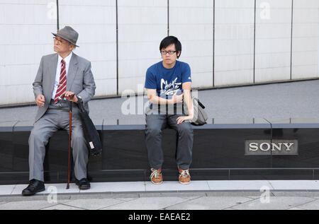 Un vecchio e un giovane uomo seduto davanti al palazzo di Sony nel quartiere di Ginza a Tokyo, 30 settembre 2014. Foto: Friso Gentsch/dpa Foto Stock