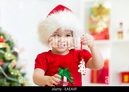 Bambino ragazza in Santa hat holding biscotti di Natale Foto Stock