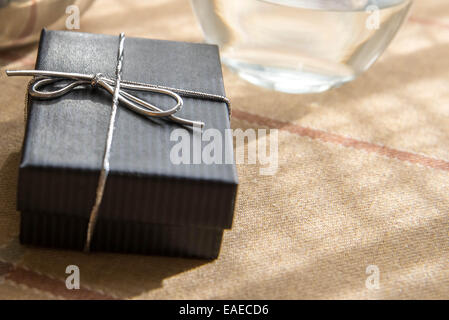 Piccoli gioielli nero confezione regalo con un arco di argento nella luce del sole di mattina Foto Stock