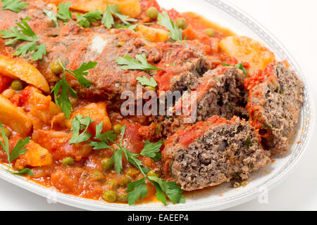 In casa polpettone cotto in salsa di pomodoro con piselli e patate. Foto Stock