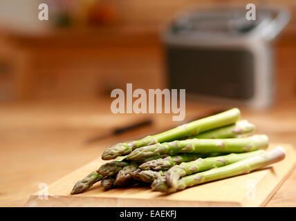 Gli asparagi spears backlit su uno sfondo di legno con coltello da cucina e radio Foto Stock