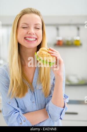Sorridente giovane donna mangiare panino Foto Stock