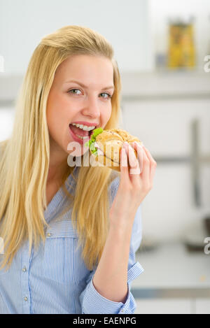 Felice giovane donna mangiare panino Foto Stock