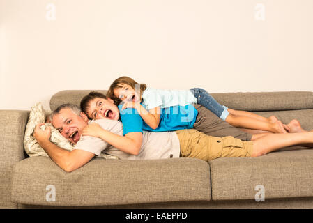 Padre e figli disteso sul divano urlando al di sopra di ogni altro Foto Stock