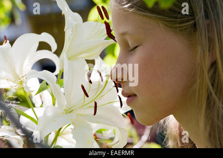 Piccola ragazza caucasica maleodoranti giglio bianco fiori closeup profilo Foto Stock
