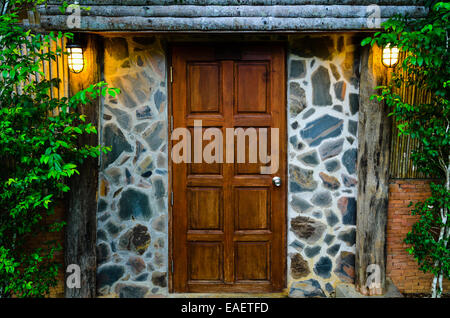 Davanti la porta di legno del residence, circondato dalla natura in serata Foto Stock