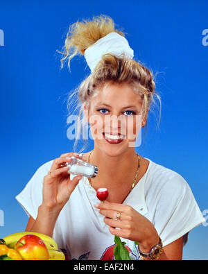 Donna bionda mangiare ravanelli con sale per la prima colazione Foto Stock