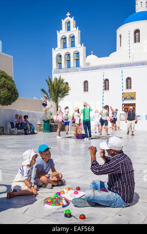 Venditore di strada e i bambini al di fuori di una chiesa Panagia Platsani Oia Santorini (Thira) Isole Cicladi Isole Greche grecia Europa Foto Stock