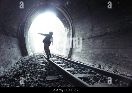 Bambino a piedi nella galleria ferroviaria. Abbigliamento vintage Foto Stock