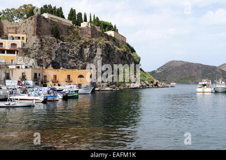 Castello di roccia e piccole imbarcazioni ormeggiate in porto Isola di Lipari Sicilia Italia Foto Stock