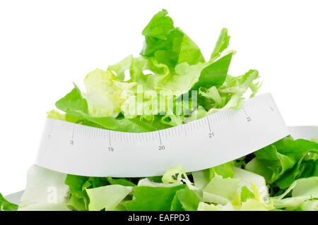 Ingrandimento di una piastra con una insalata verde e un nastro di misurazione, che simboleggiano la dieta di un concetto o di mantenersi in forma Foto Stock