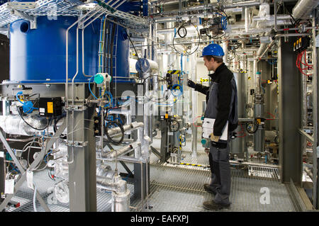 Engineer per le energie rinnovabili e le tecnologie ambientali e dipendente di Sunfire GmbH, Bosse Schluz, illustra le funzioni di un reattore di conversione (blu) durante un press tour presso il Sunfire GmbH stabilimento di Dresda, Germania, 14 novembre 2014. Dresda-basato Sunfire vuole effettuare una sostituzione di petrolio al di fuori dell'acqua e biossido di carbonio con un milione di euro impianto pilota. La potenza al liquido processo converte acqua e biossido di carbonio in un liquido sintetico come carburante benzina, diesel e karosine utilizzando sistemi eco-power. Foto: ARNO BURGI/dpa Foto Stock