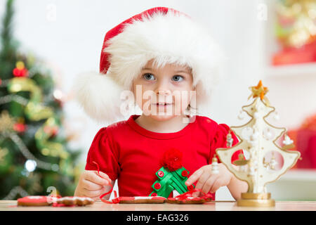 Bambino ragazza in Santa hat rendendo le decorazioni di Natale Foto Stock