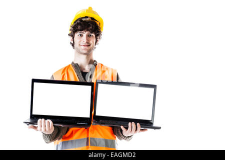 Un ingegnere o un architetto che indossa un casco e un giubbotto e trattenere due computer portatili con schermo vuoto. Isolato su bianco Foto Stock