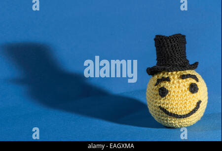 Giallo a maglia emoticon con bowler su sfondo blu Foto Stock