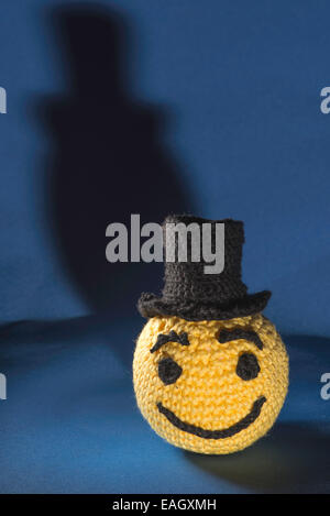 Giallo a maglia emoticon con bowler su sfondo blu Foto Stock