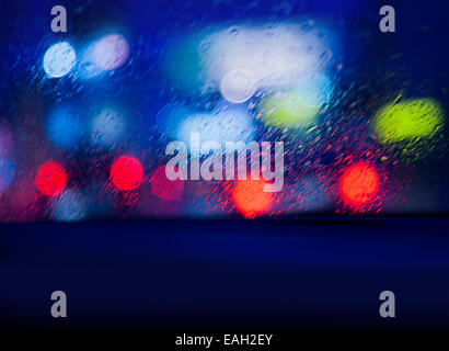 Vista dall'auto nella notte piovosa, cercando su sfocata incandescente luci auto attraverso il parabrezza, il traffico automobilistico nelle ore notturne Foto Stock