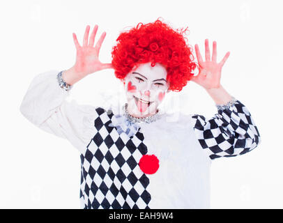 Bambina in parrucca rosso, trucco e vestito in posa come un clown. Foto Stock