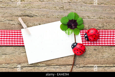 Trifoglio Leafed, ladybugs e carta sul pannello di legno Foto Stock