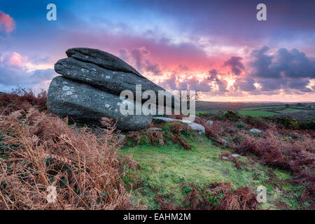 Sunrise sopra un grande masso di granito sul robusto a brughiera Helman Tor vicino a Bodmin in Cornovaglia Foto Stock