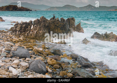 Dure le onde si infrangono sulla spiaggia rocciosa di bevuto Bay di San Giovanni Foto Stock