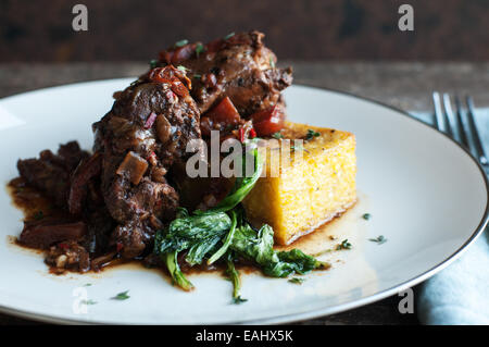 Polenta con aceto balsamico pollo brasato con la deliziosa cucina di stagione saltata di verdi Foto Stock