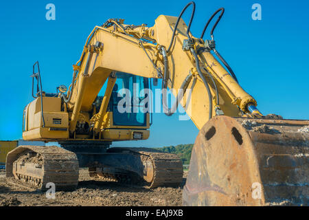 Escavatore giallo su blu sullo sfondo del cielo Foto Stock