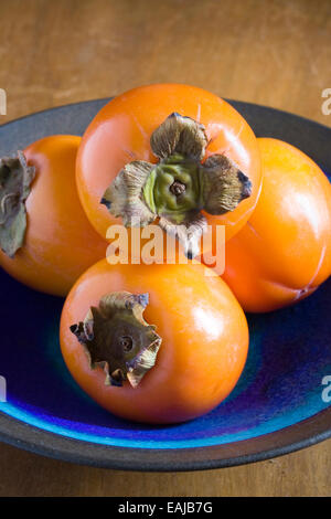 Persimmon frutto in una ciotola blu. Foto Stock