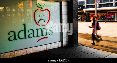 Una donna cammina passato graffiti di un ramo chiuso di adams abbigliamento per bambini store su moor street nel centro della città di Sheffield Foto Stock