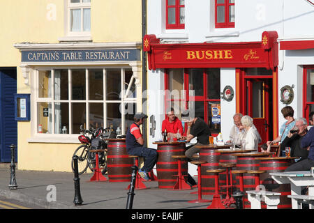 Persone sedute e di bere al di fuori di un pub del porto in Irlanda a Baltimora, West Cork, nella contea di Cork, Irlanda. Foto Stock