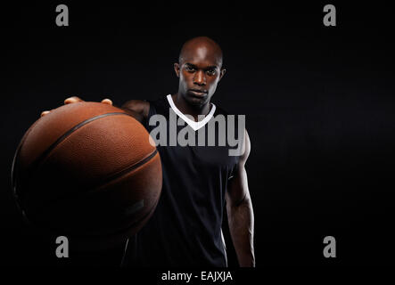 Immagine del giovane americano africano uomo sportive in jersey tenendo un basket. Giocatore di pallacanestro professionale contro il nero. Foto Stock