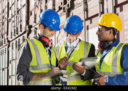 Imprenditori e lavoratori parlando vicino ai contenitori di carico Foto Stock