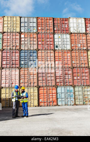 Imprenditore e lavoratore parlando vicino ai contenitori di carico Foto Stock