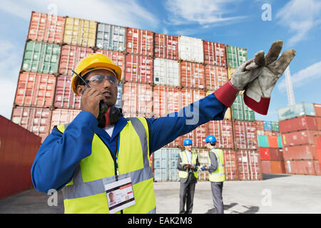 Lavoratore utilizzando un walkie-talkie vicino ai contenitori di carico Foto Stock