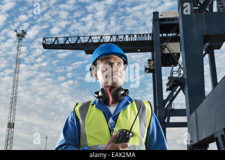 Lavoratore sorridendo vicino a gru di carico Foto Stock