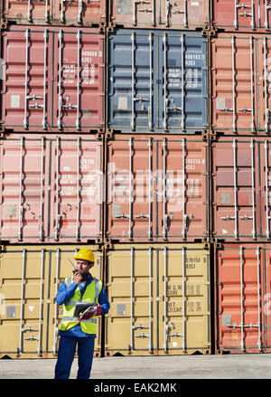 Lavoratore utilizzando un walkie-talkie vicino ai contenitori di carico Foto Stock