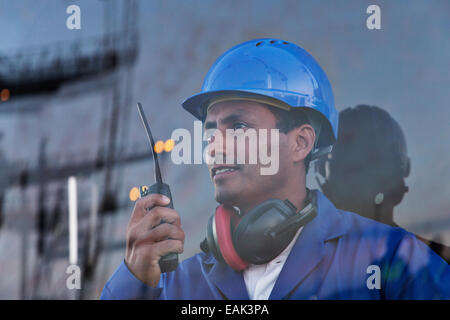 Lavoratore azienda walkie-talkie vicino a finestra Foto Stock