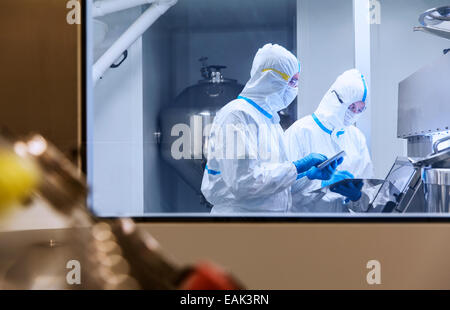 Gli scienziati in abiti puliti utilizzando compresse digitale nell'esperimento in laboratorio Foto Stock