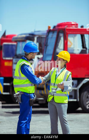 Imprenditrice e lavoratore stringono le mani vicino al camion Foto Stock