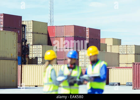 Imprenditore e lavoratori parlando vicino ai contenitori di carico Foto Stock