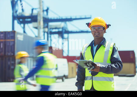 Lavoratore in piedi vicino ai contenitori di carico Foto Stock