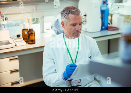 Scienziato prendendo appunti sulla sperimentazione in laboratorio Foto Stock