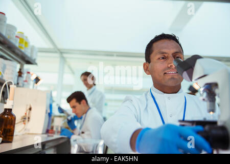 Scienziato campione esaminato al microscopio in laboratorio Foto Stock