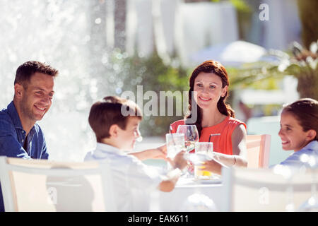 Famiglia con due bambini il sollevamento toast a tavola all'aperto Foto Stock