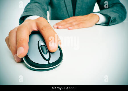 Un imprenditore seduto in una scrivania utilizzando un mouse del computer Foto Stock