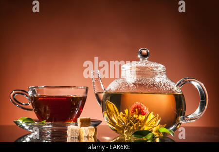 Teiera e tazza di tè in fiore su vetro Foto Stock