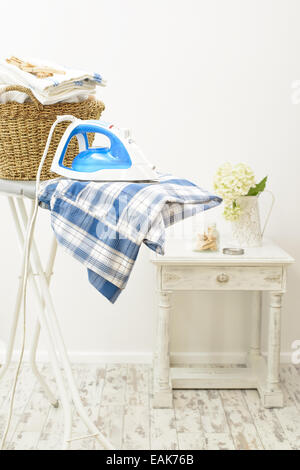 Appena premuto vestiti sulla tavola da stiro in lavanderia Foto Stock