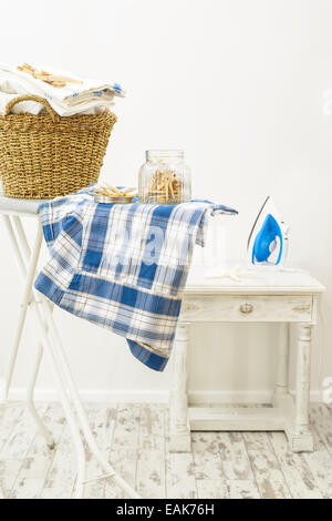 Vaso di mollette e cesto della biancheria fresca con ferro in background Foto Stock