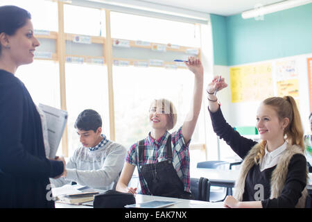 Gli studenti con il loro insegnante in classe, sorridente e bracci di sollevamento Foto Stock